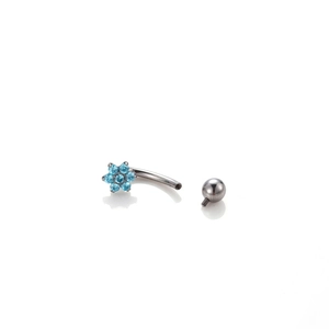 Titanium flower belly ring with blue zircon inlay on white reflective surface