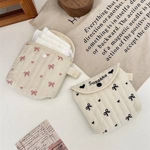 Dettaglio di pochette trapuntate in cotone con ricami a fiocco per assorbenti igienici