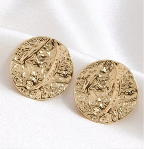 Macro detail of round golden stainless steel stud earrings with irregular hammered texture