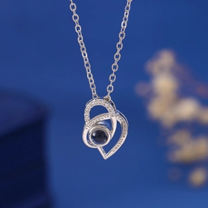 Detail of silver heart projection necklace with I love you to the moon and back engraving