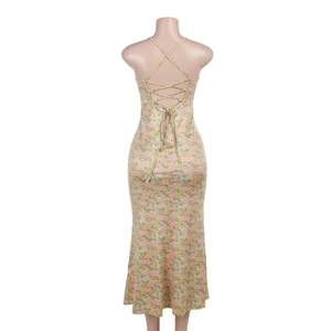 Vue détaillée du dos d'une robe longue fleurie avec laçage et fleurs roses sur fond vert