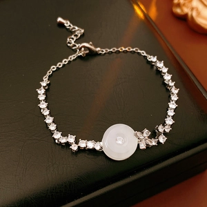 Macro detail of silver zircon bracelet with white chalcedony on black leather background