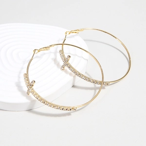 Gold plated hoop earrings with sparkling crystal cross pendants on a white display