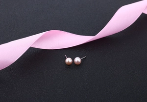 Macro shot of light pink freshwater pearl earrings with silver posts on grey background