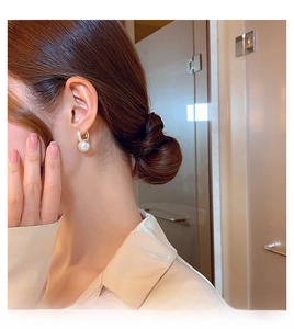 Close-up of elegant pearl drop earrings with gold finish on model in soft home setting