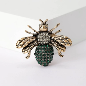 Detail of vintage gold bee brooch featuring sparkling green and clear rhinestones