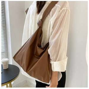 Brown large capacity tote bag with knotted shoulder strap detail shown on model back view