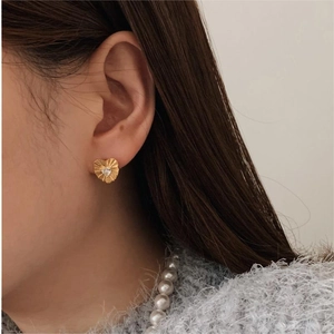 Close-up of heart stud earrings in gold with zircon stone worn by a model