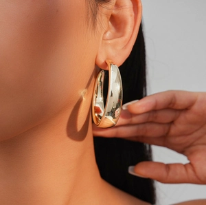 Close-up of chunky gold hoop earring with a polished metallic finish on a model's ear