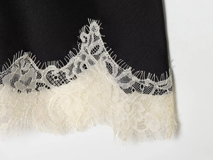 Detailed macro view of black satin fabric with intricate white eyelash lace trimming