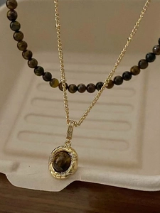 Close-up of gold-plated tiger eye necklace with vintage pendant and crystal accents