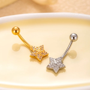 Macro shot of gold and silver star belly rings with pavé zircon stones on a tray
