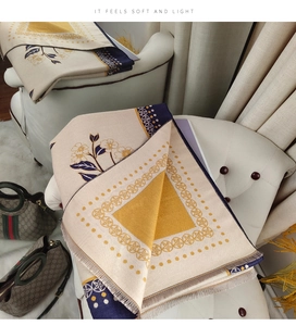 Detail of warm imitation cashmere scarf with navy floral patterns on soft beige fabric