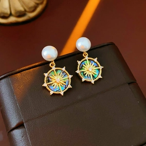 Macro detail of gold plated pearl earrings with shell inlay and sunburst stone pattern