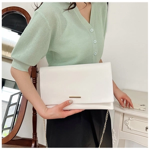 Detail of white PU leather envelope bag with gold chain strap and metal buckle