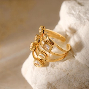 Bague multicouche en acier doré avec zircons géométriques sur support en pierre blanche