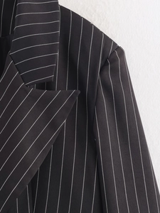 Detailed close-up of the notch lapel and shoulder of a black pinstripe blazer