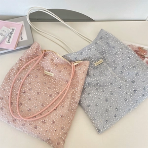 Detailed shot of pearl-beaded lace mesh tote bags with delicate handles and woven label
