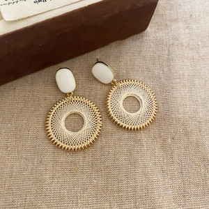 Close-up of bohemian grid patterned hoop earrings with golden wire weave on linen