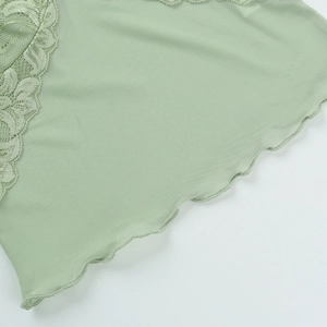 Macro detail of scalloped lace hem on a light green mesh top with intricate floral patterns