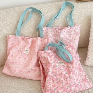 Detail of pink floral quilted tote bags with light blue handles on a cozy cream sofa
