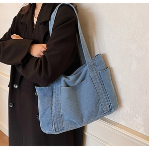 Detailed close-up of light blue denim hobo bag featuring side pockets and fine fabric texture