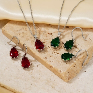 Luxurious pear-cut teardrop necklace and earrings set on stone and silk background