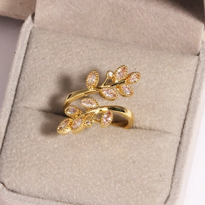 Détail macro d'une bague feuille d'olivier dorée avec zircone rose en boîte