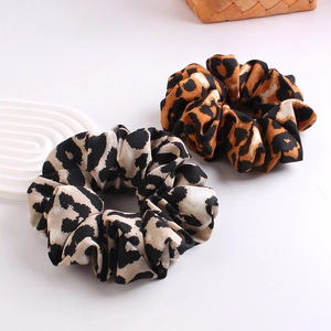 Close-up of brown and gray leopard print fabric scrunchies on a white surface