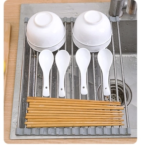 Detail of foldable stainless steel roll-up dish drying rack over sink with utensils