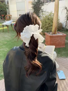 Detailed view of a white lace eyelet embroidery scrunchie styled on a ponytail in sunlight