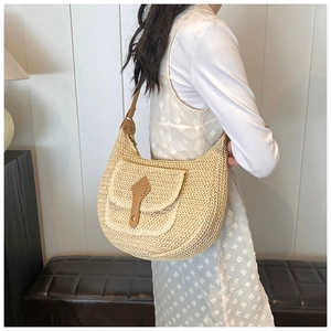 Detailed close-up of a woven straw shoulder bag with leather accents and metal rivet