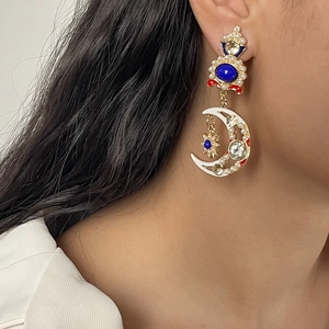 Dettaglio di orecchini vintage luna e stella con pietre blu indossati