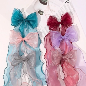 Elegant organza bow hair clips with long tassels in six vibrant colors on a flat lay set