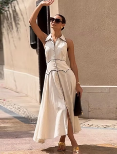 Détail d'une robe chemise sans manches crème avec passepoil noir et boutonnage sur le devant