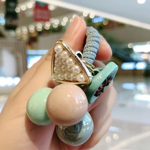 Detail of colorful beads and pearl triangle accent on a light blue elastic hair tie