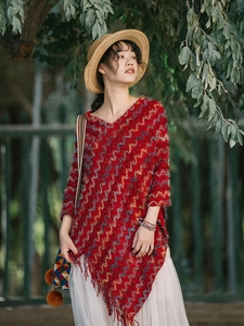 Détail du poncho en tricot bohème rouge avec motifs ethniques et finitions à franges