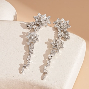 Detail of silver drop earrings with floral charms and crystals on stone decor