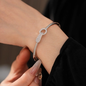 Close-up of gold plated silver bangle with cubic zirconia buckle on model's wrist