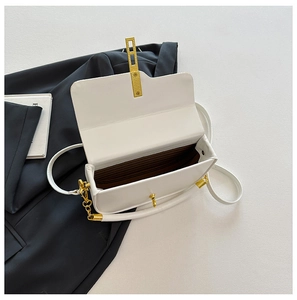 Detail view of white minimalist box bag with golden hardware and textured interior lining