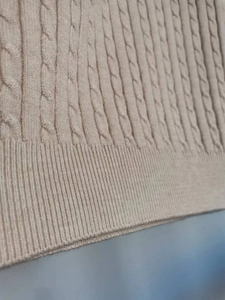 Dettaglio macro della maglia a trecce beige e della trama del bordo a coste