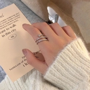 Detailed close-up of a silver-tone double-layer zircon ring worn with a soft knit sweater
