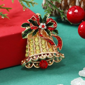Christmas bell brooch with red crystals and green enamel on a festive holiday background