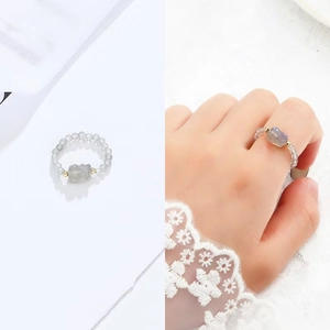 Detail view of a beaded ring with a carved Pixiu charm and small gemstones on a white background