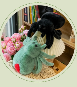 Detail of plush black spider and green insect toys with red heart patterns on back