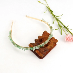 Detail of handmade gold double-row headband with natural green crystal stones on wood