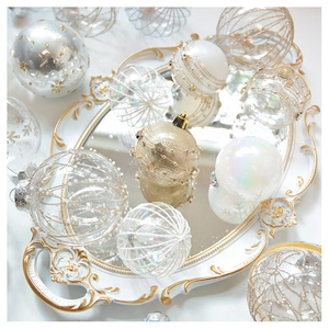 Close-up of champagne lace and pearl Christmas ball ornaments on a golden vintage tray
