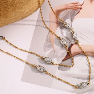 Close-up of dual-tone 18K gold and silver bead chain necklace on a fashion magazine