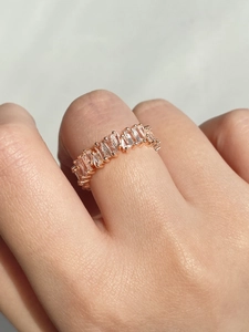Close-up of a rose gold ring with rectangular zircons worn on the index finger