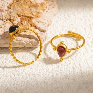 Detail of gold adjustable rings with black oval obsidian and red waterdrop gemstone